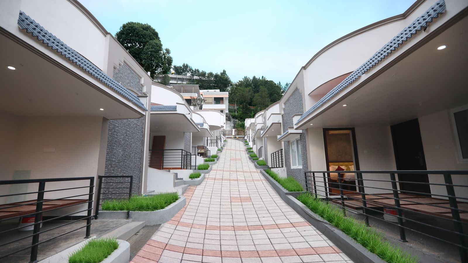 A bright exterior shot of the pathway going upwards at WOW Naturefull Resorts, Yercaud, with cottages on either side of the pathway.