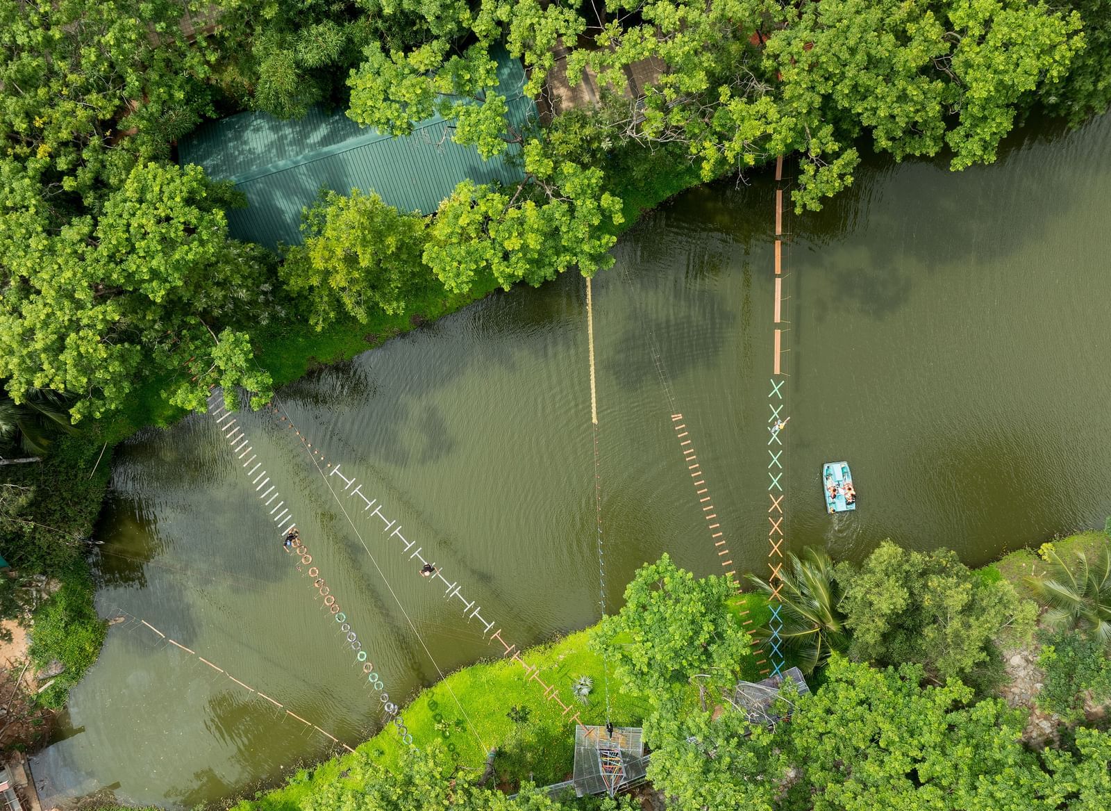 An aerial perspective captures a serene body of water, possibly a river or lake, bordered by vibrant green trees | RD's Nature Retreat, Bangalore