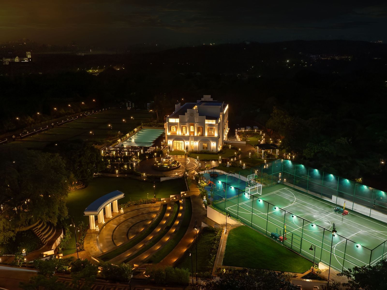 A bird's eye view of the Imperial Goa during the night featuring a huge swimming pool and a warmly lit exterior of our resort.