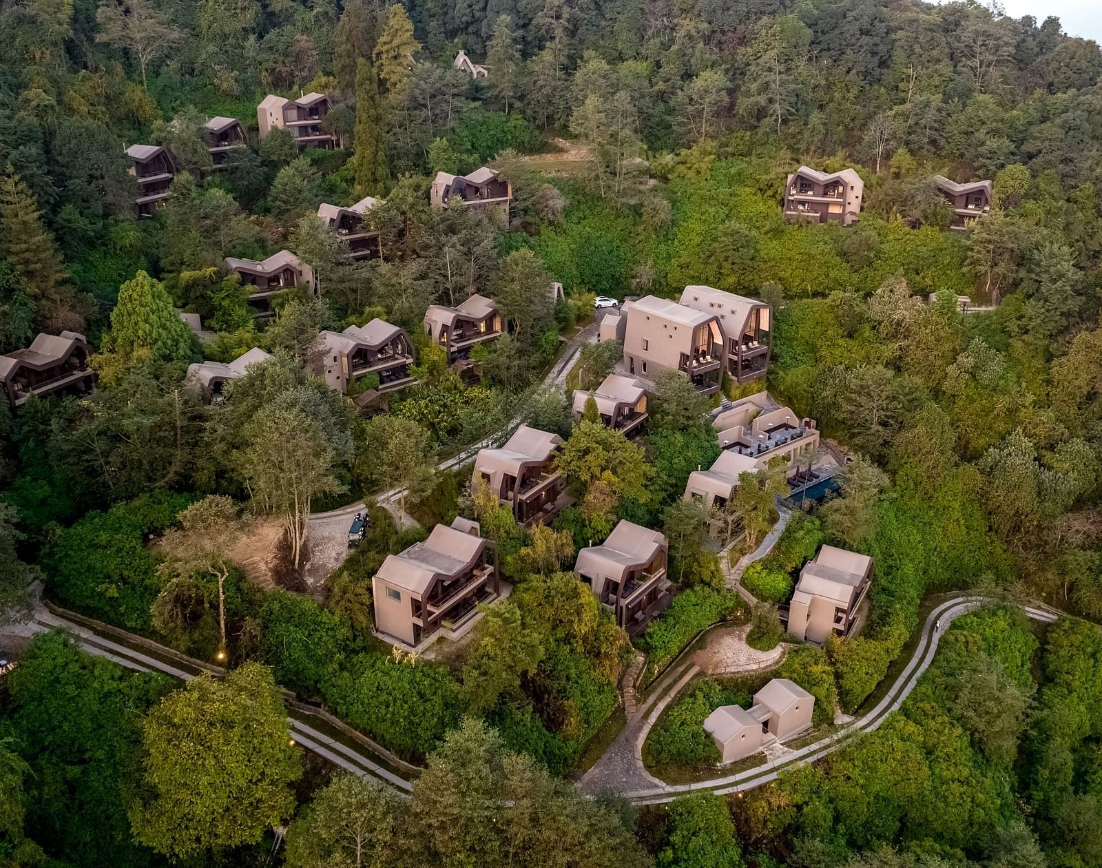 erial view of a resort nestled in a dense forest, with numerous small lodges 