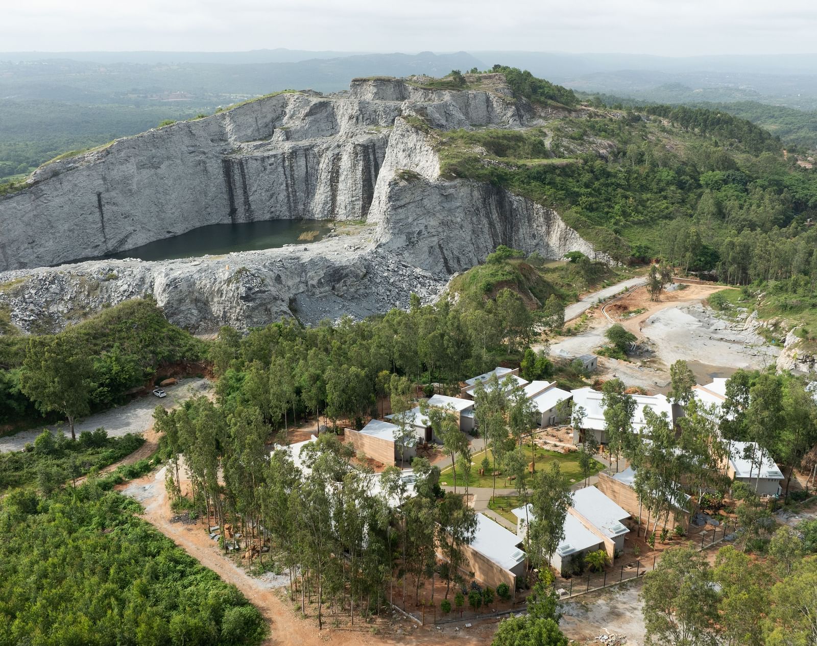 An expansive aerial view showing a large quarry or excavation site with scattered buildings and vegetation | Gaia Studio | RD's Nature Retreat, Bangalore