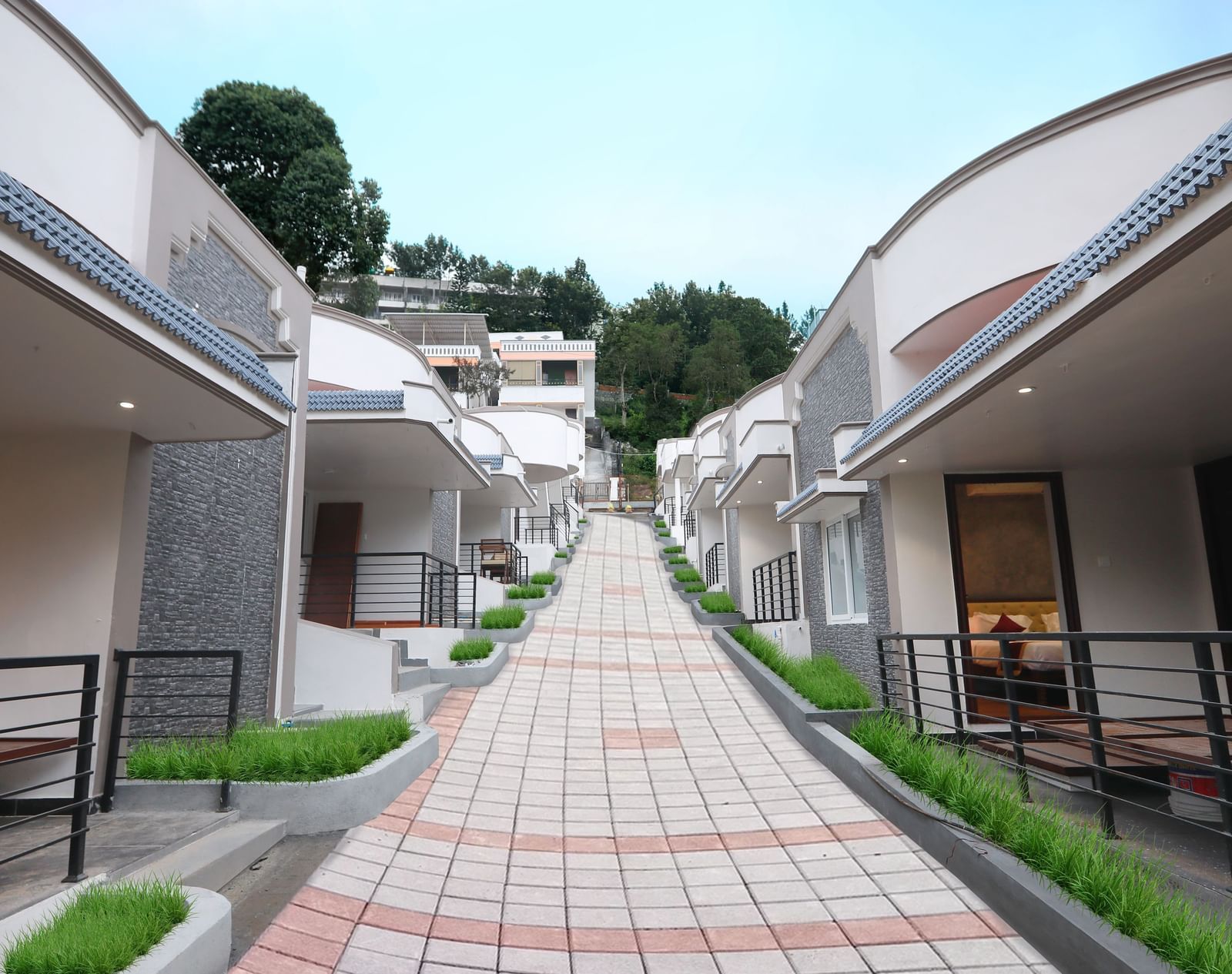 A bright exterior shot of the pathway going upwards at WOW Naturefull Resorts, Yercaud, with cottages on either side of the pathway.