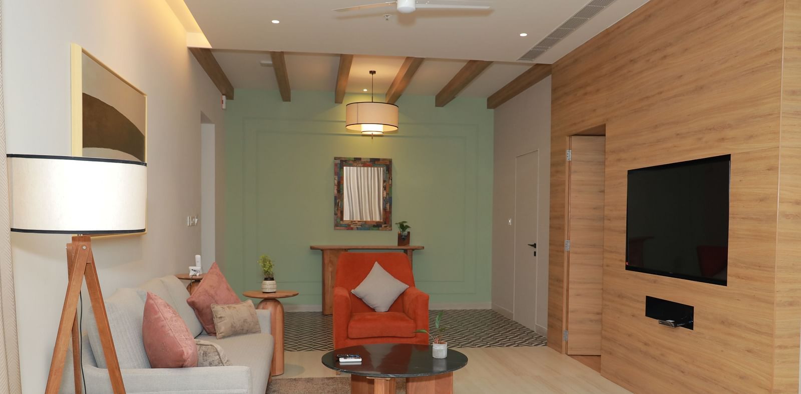 A couch positioned in front of a wall-mounted television, with ambient lighting from above - Regency Tuticorin by GRT Hotels