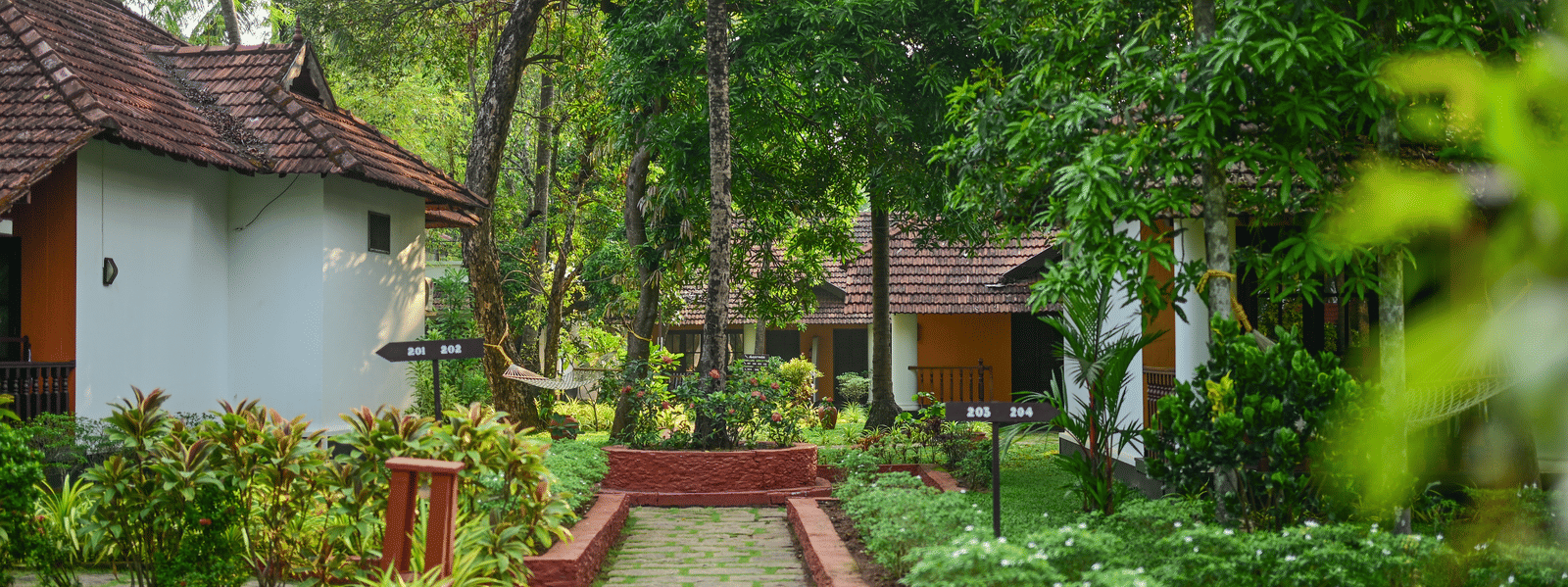 A stone-paved garden path leading through the lush tropical grounds and guest villas at Ayur On The Beach Nattika.