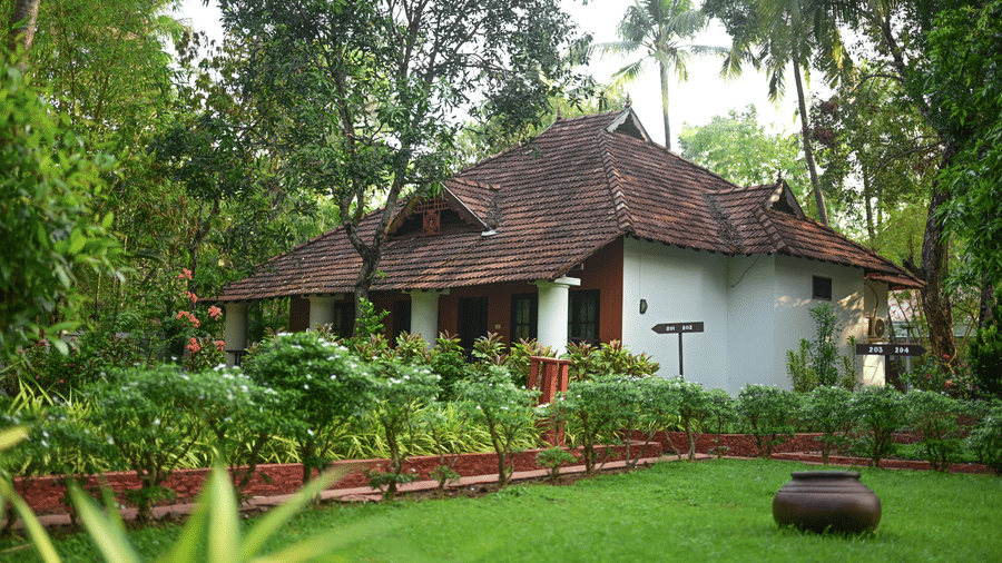 The exterior of a traditional villa at Ayur On The Beach Nattika, surrounded by lush tropical gardens and trees.