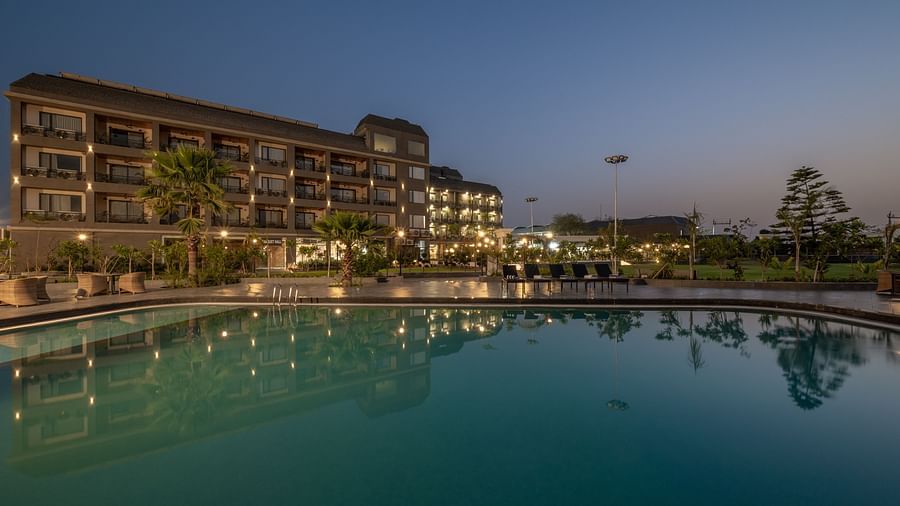 Swimming pool and hotel building at Hotel Highway King, Bagru, with poolside lighting and landscaped garden in the evening.
