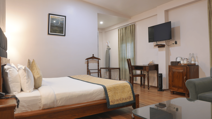 A bedroom at The Heritage Club Tripura Castle Hotel and Spa, Shillong featuring a king size bed, a study desk, a television, and a seating area.  