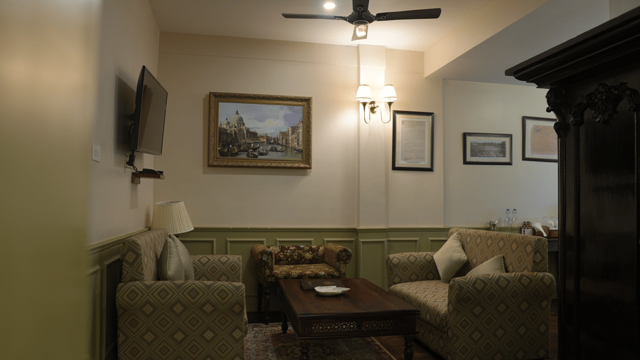 A living room at The Heritage Club Tripura Castle Hotel and Spa, Shillong featuring 2 sofas, a coffee table, a wall-mounted television, and wall art.  