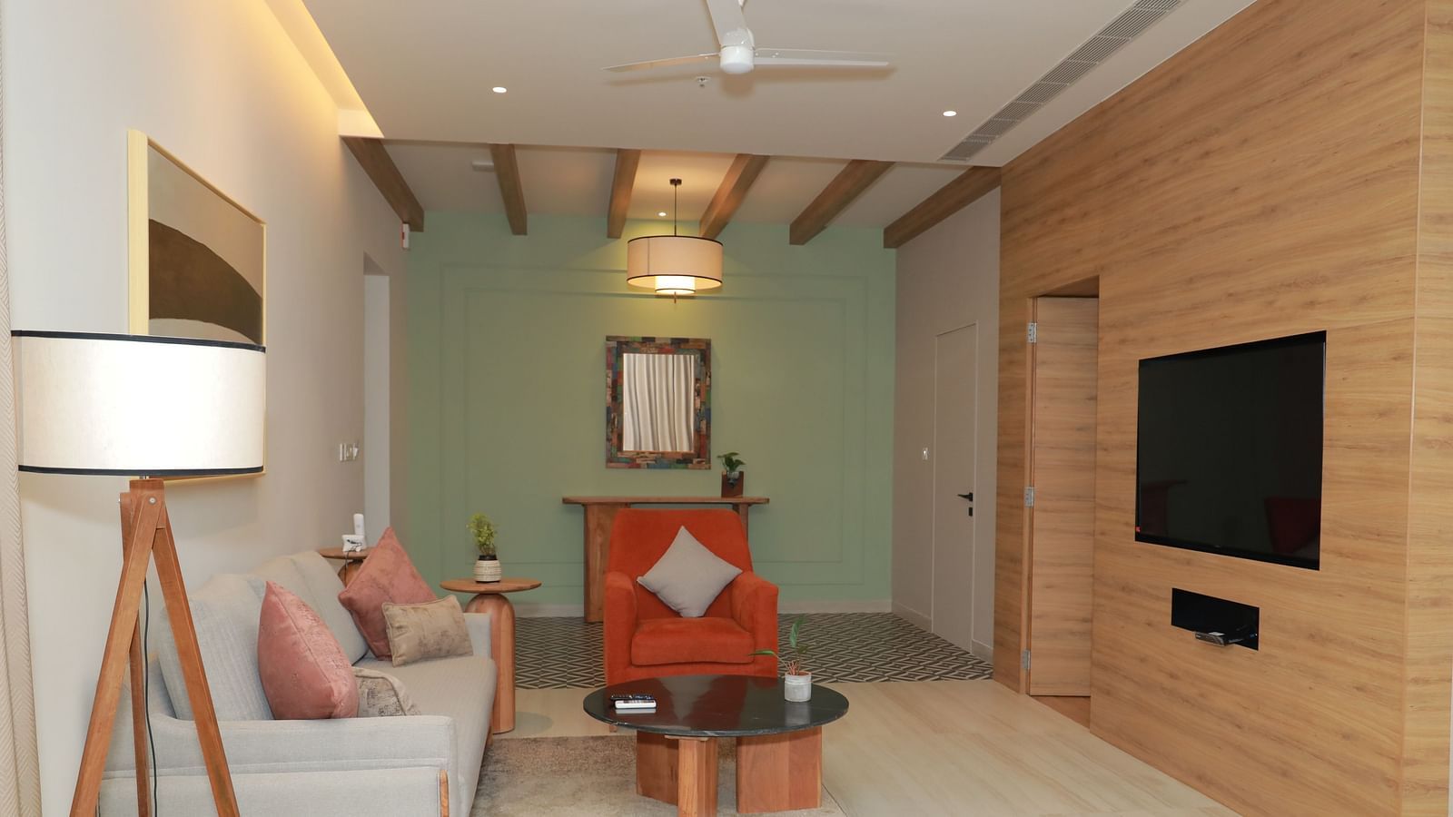 A couch positioned in front of a wall-mounted television, with ambient lighting from above - Regency Tuticorin by GRT Hotels