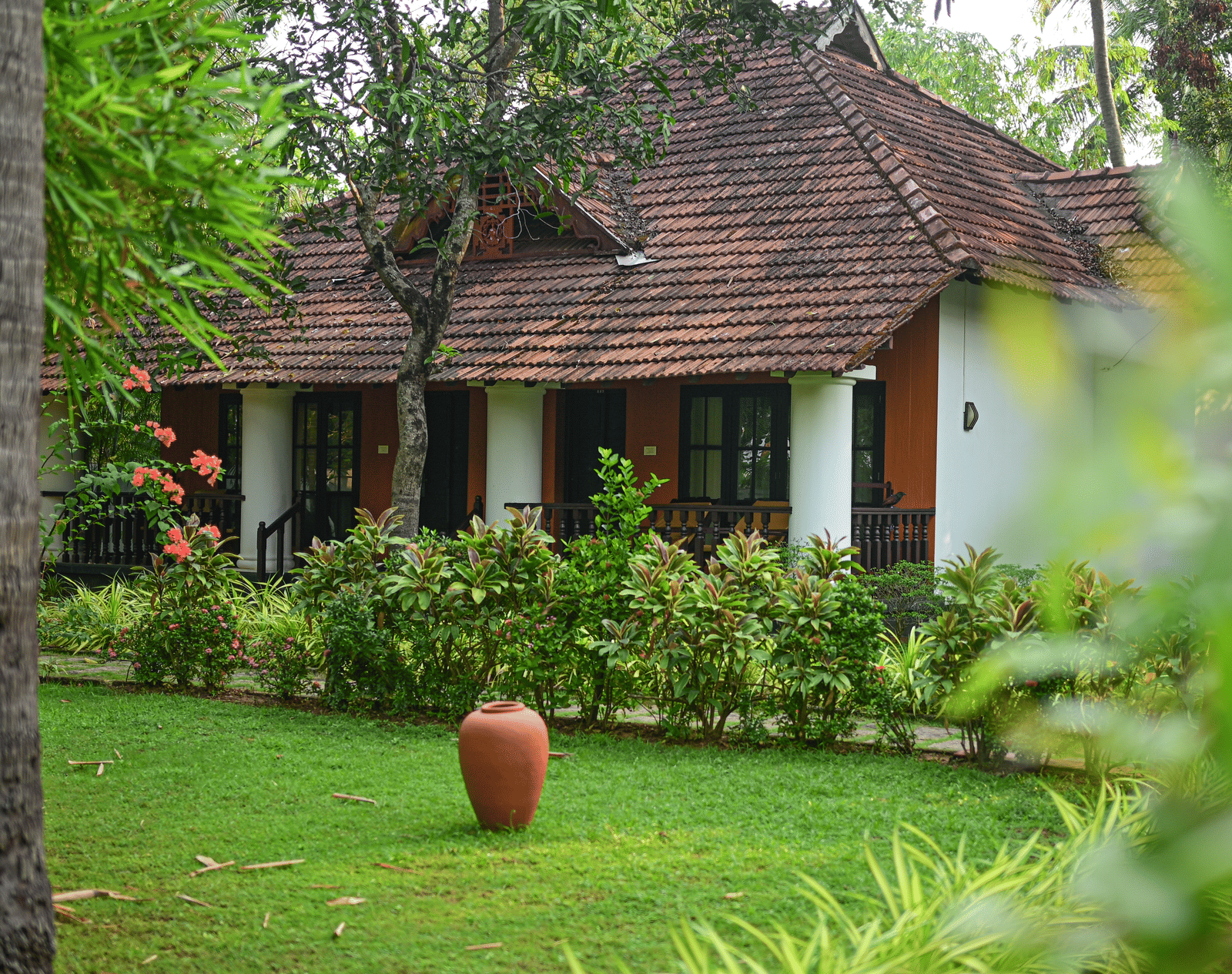 A charming cottage at Ayur On The Beach Nattika set within a lush tropical garden with manicured lawns and shrubs.