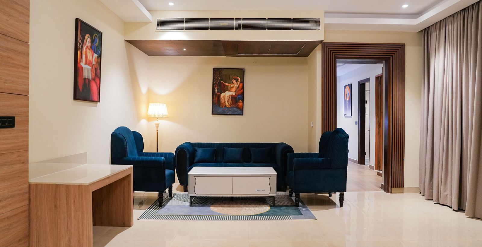A comfortable and stylish living area at the Empress Suite at The Meriton, furnished with a deep blue sofa, a coffee table, and an accent chair.