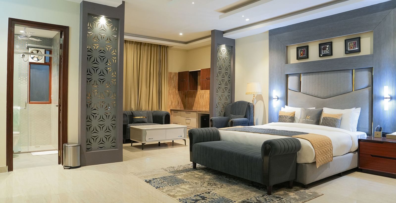 A wide view of the Premium Room at The Meriton, combining a sleeping area with a large king size bed and an adjoining sitting area with a chaise lounge.