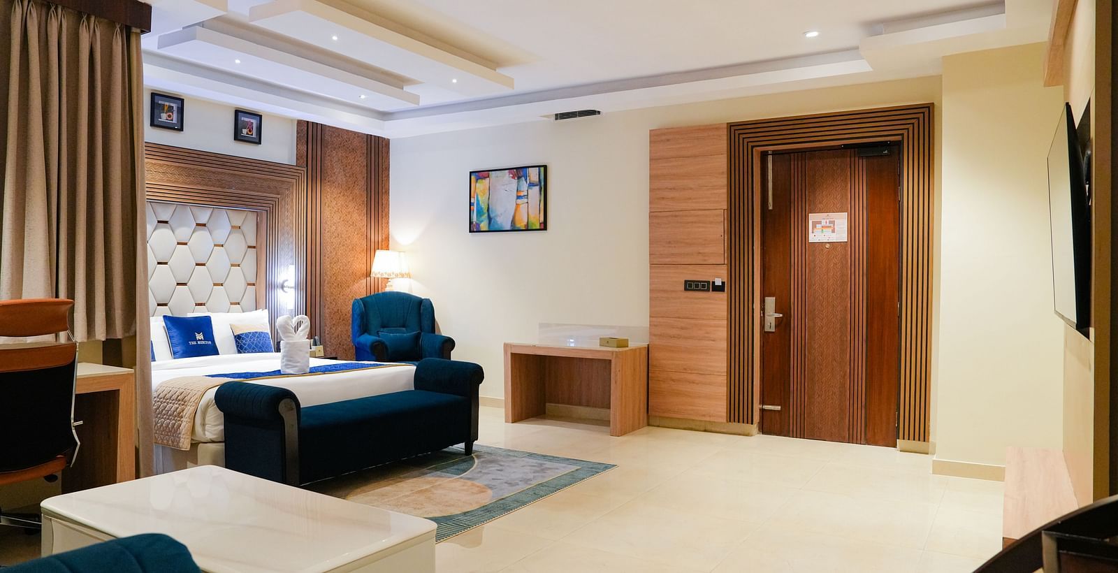 A welcoming living area at the Presidential Suite at The Meriton, showing a comfortable sofa, a patterned rug, and a glimpse of an adjoining bedroom or entrance.