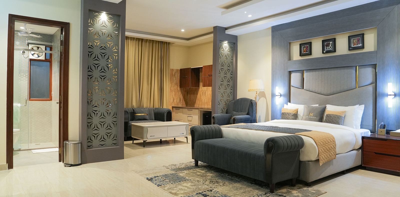 A wide view of the Premium Room at The Meriton, combining a sleeping area with a large king size bed and an adjoining sitting area with a chaise lounge.