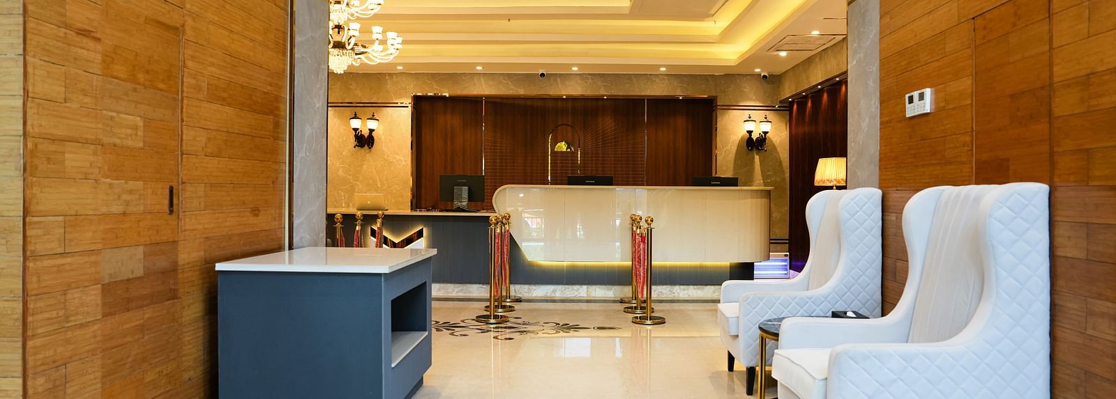 A welcoming reception area at The Meriton, with stylish white armchairs, a sleek counter, and tasteful lighting fixtures.