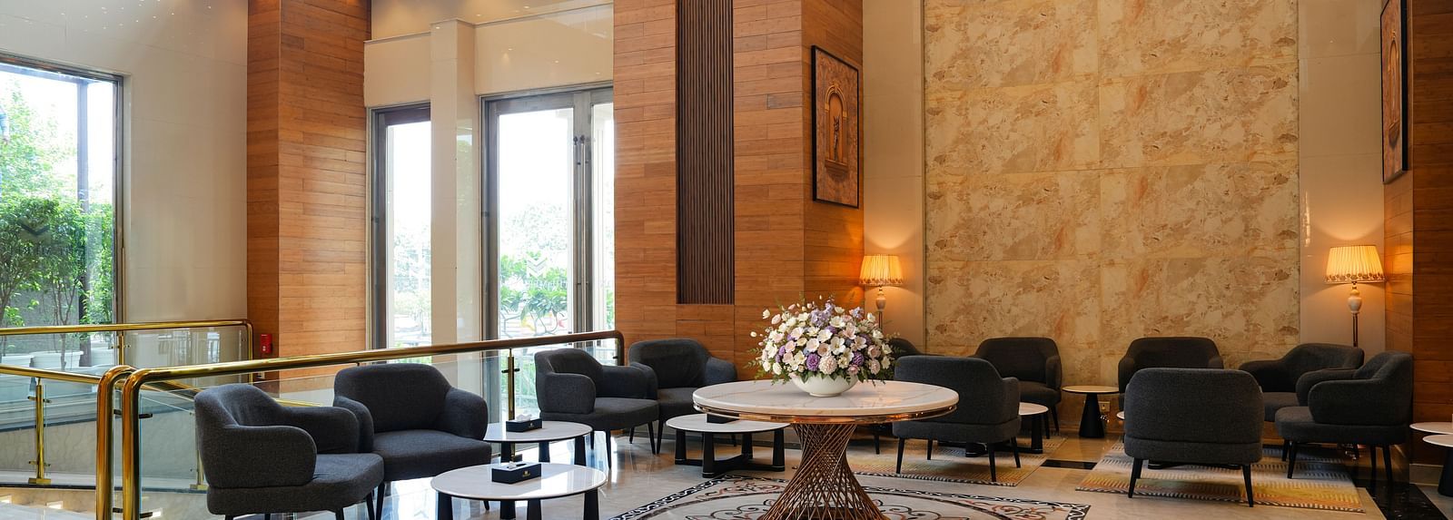 A wide view of The Meriton's sophisticated common area, featuring dark upholstered seating, round tables, and decorative wall panels, suggesting a lounge or bar.