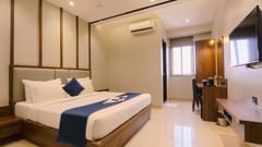 An image of a bedroom featuring a double size bed, flat TV screen, an AC, a work desk and chair, and a cabinet table below the TV - Magnus Fortune House, Magarpatta