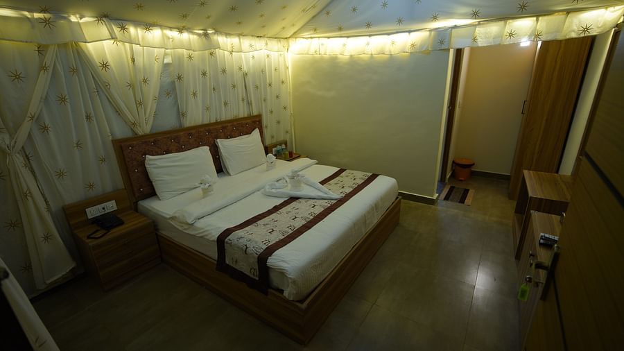Double bed in the spacious Tent villa of GK Hill View Resort spaciously furnished with bedside tables, cabinets, wardrobe.