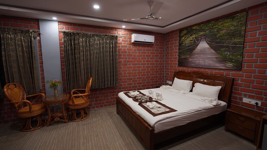 Premier Rooms in GK Hill View Resort furnished with double bed, bedside tables, sitting area for two, wall-mounted AC, curtained windows and romantic lighting.