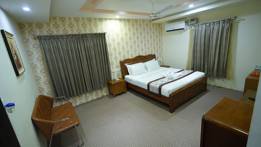 Themed Villas of GK Hill View Resort furnished with a double bed, wall-mounted AC, a chair and curtained windows.