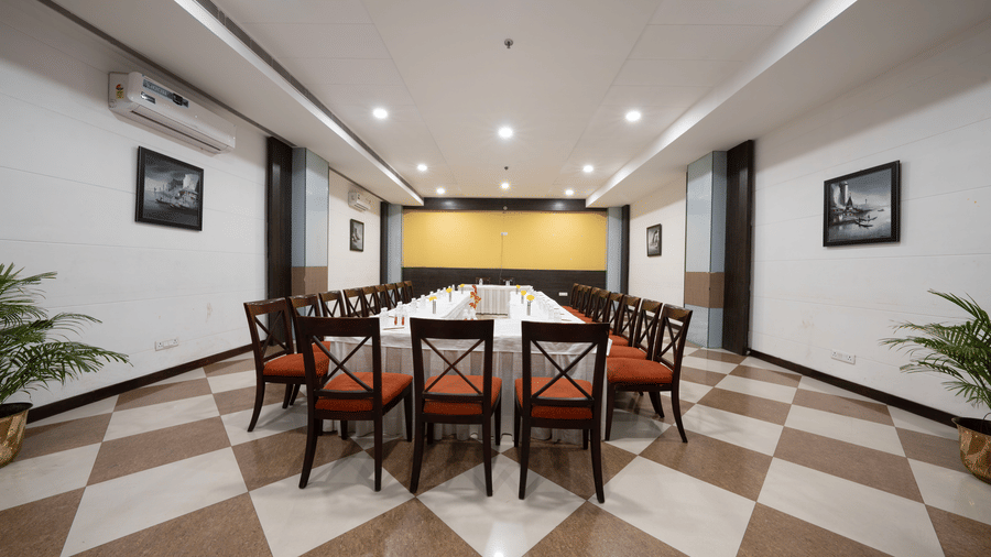 A conference room with a rectangular table setup, tiled flooring, and framed pictures on the walls | HHI Varanasi