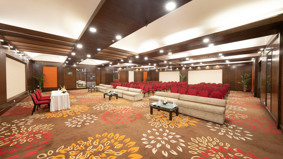 A conference room with couches in the front, rows of chairs, and two screens | HHI Varanasi