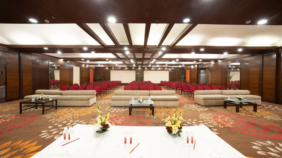 A large meeting room with dark wood panels and rows of chairs and a screen | HHI Varanasi