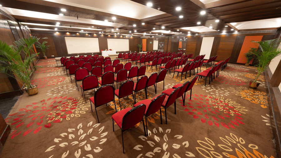A conference room with red chairs, a presentation screen, and potted plants | HHI Varanasi