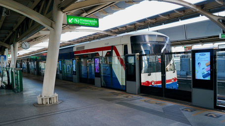 An overview of the BTS Skytrain at the terminal near QSNCC Bangkok during daytime with a train waiting.