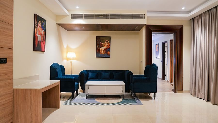 A comfortable and stylish living area at the Empress Suite at The Meriton, furnished with a deep blue sofa, a coffee table, and an accent chair.