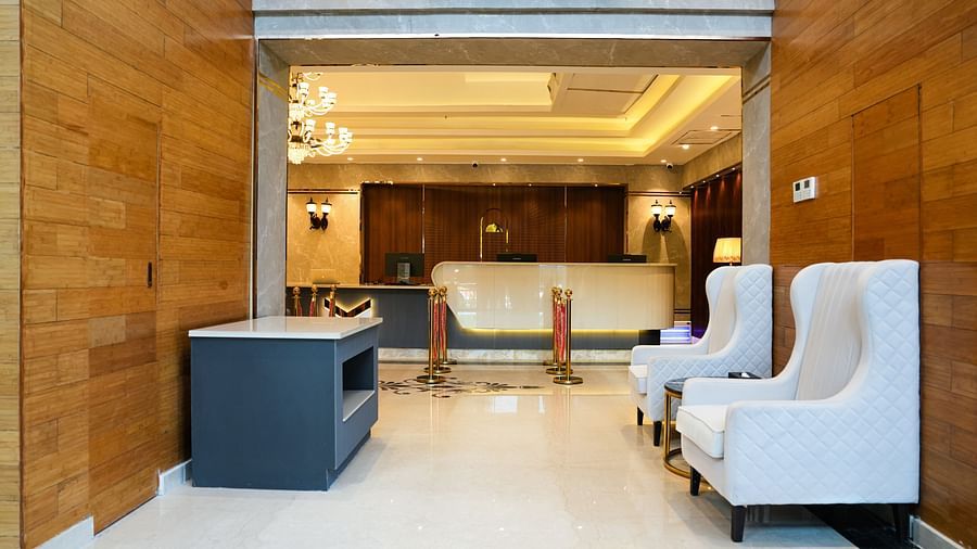 A welcoming reception area at The Meriton, with stylish white armchairs, a sleek counter, and tasteful lighting fixtures.