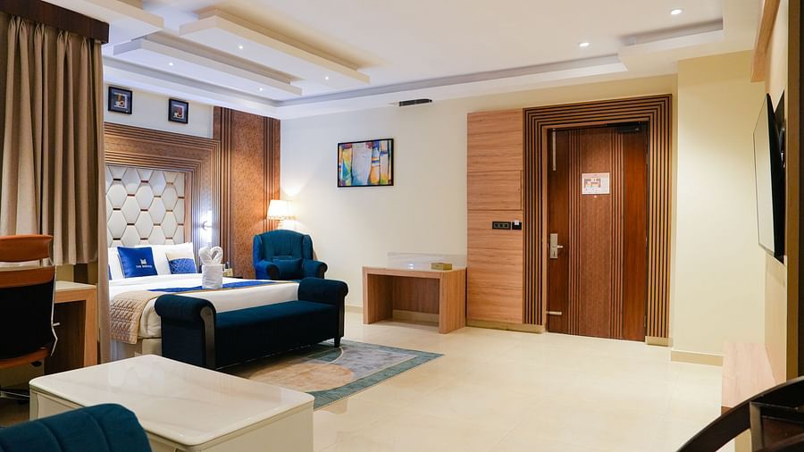 A welcoming living area at the Presidential Suite at The Meriton, showing a comfortable sofa, a patterned rug, and a glimpse of an adjoining bedroom or entrance.
