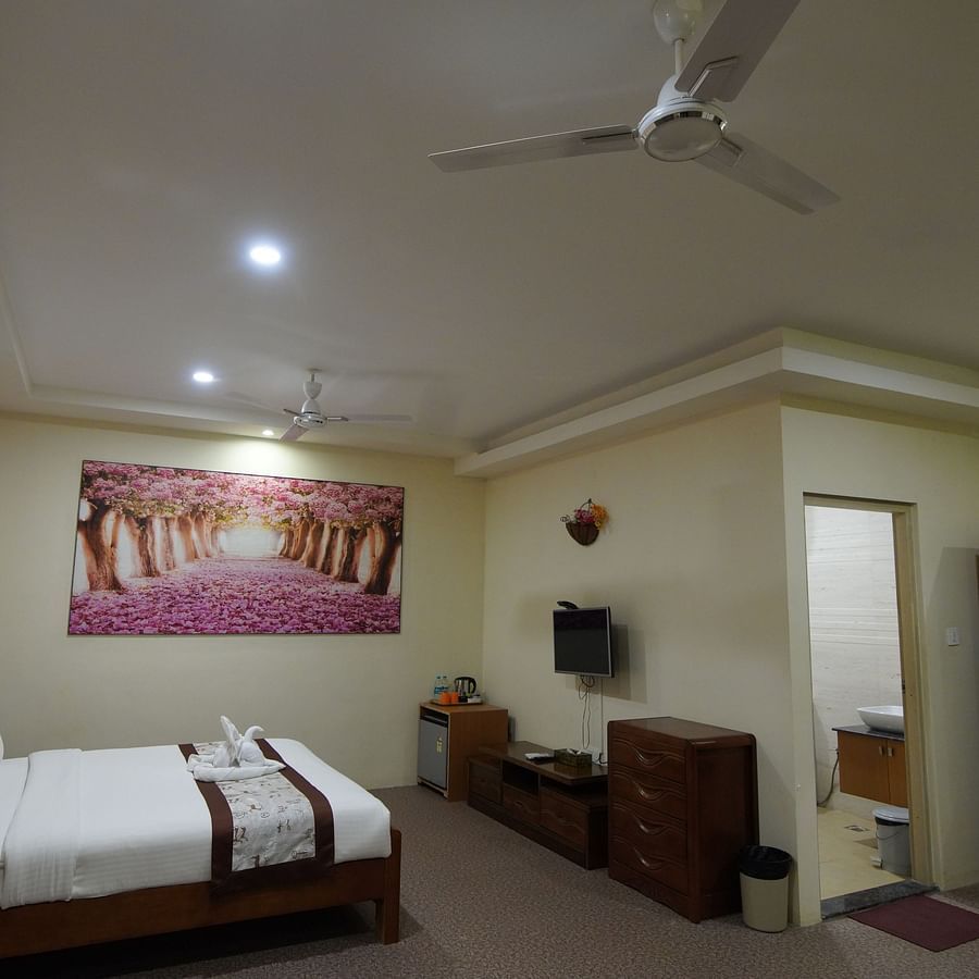 Themed Villas of GK Hill View Resort furnished with a double bed, wall-mounted AC, a chair and curtained windows.