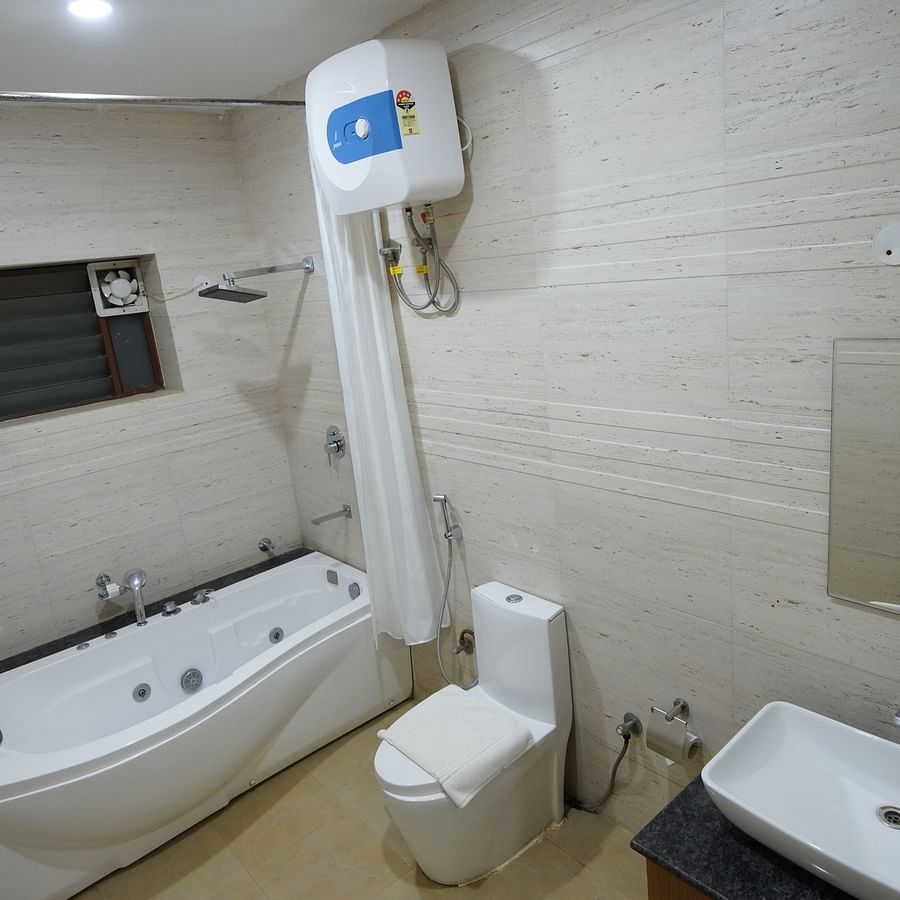 The bathroom of the Themed Villa is furnished with a Jacuzzi, sink, wall-mounted heater and western commode.- GK Hill View Resort
