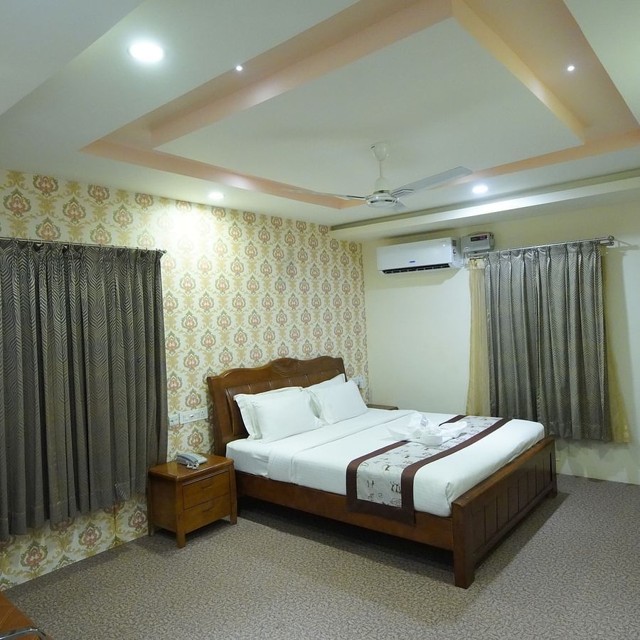 Themed Villas of GK Hill View Resort furnished with a double bed, wall-mounted AC, a chair and curtained windows.