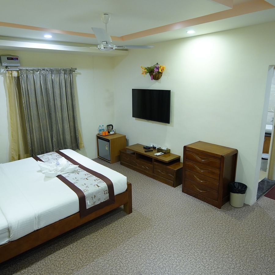 Double bed of the Themed Villa of GK Hill View Resort furnished alongside a wall-mounted TV, a cabinet, wall-mounted AC.