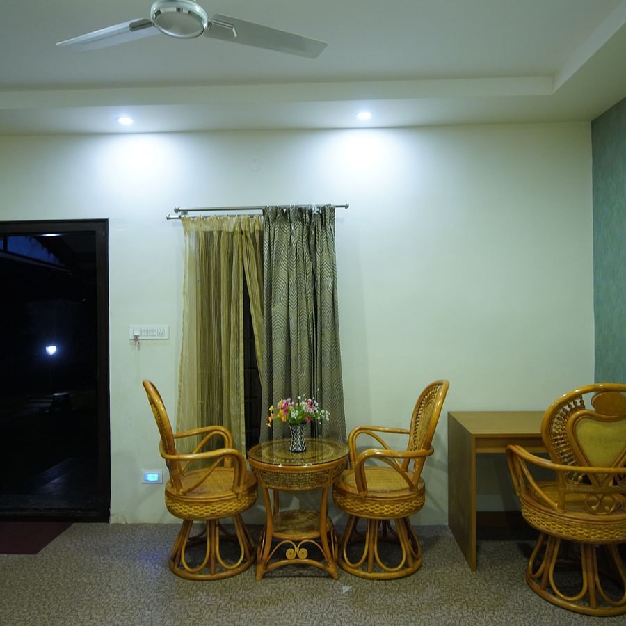 Sitting area placed beside a curtained window and work desk in the spacious Themed Villa of GK Hill View Resort.