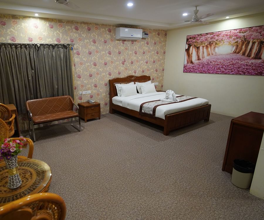 Themed Villas of GK Hill View Resort furnished with a double bed, wall-mounted AC, a chair and curtained windows.