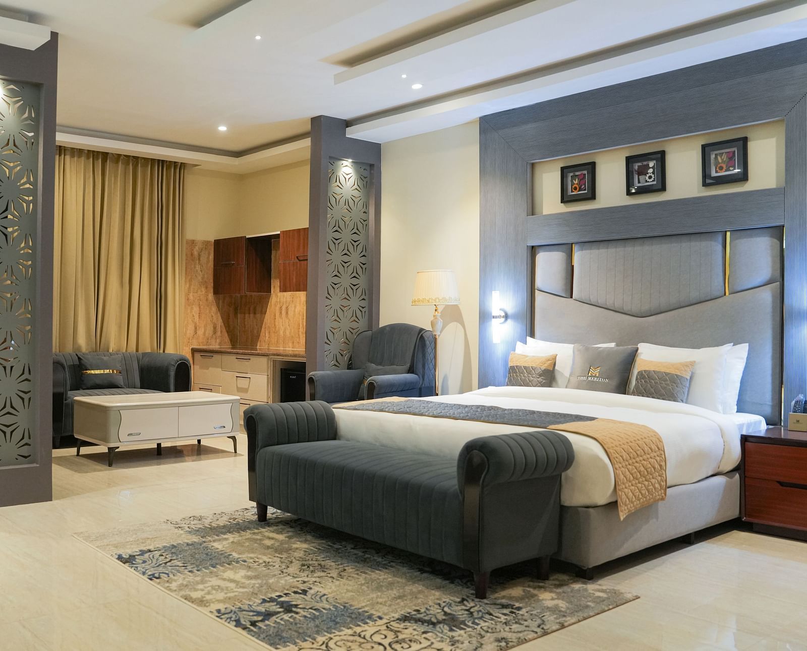 A wide view of the Premium Room at The Meriton, combining a sleeping area with a large king size bed and an adjoining sitting area with a chaise lounge.