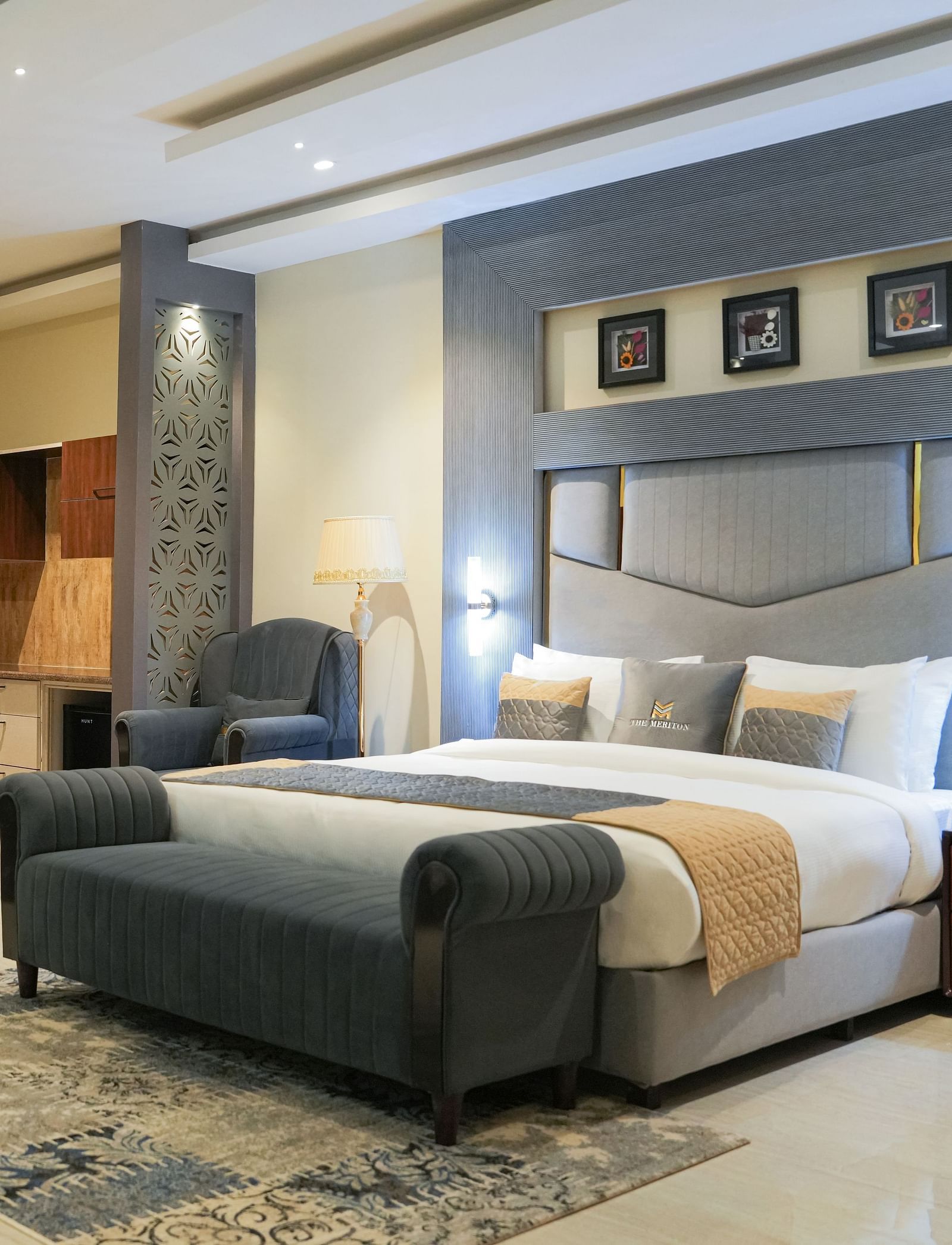A wide view of the Premium Room at The Meriton, combining a sleeping area with a large king size bed and an adjoining sitting area with a chaise lounge.
