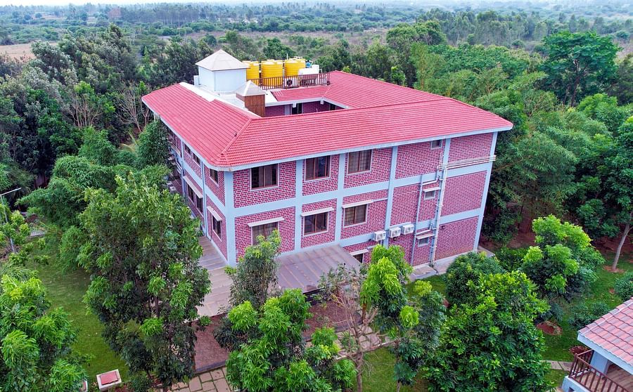 Aerial view of the exterior of the GK Hill View Resort surrounded by lush greenery.