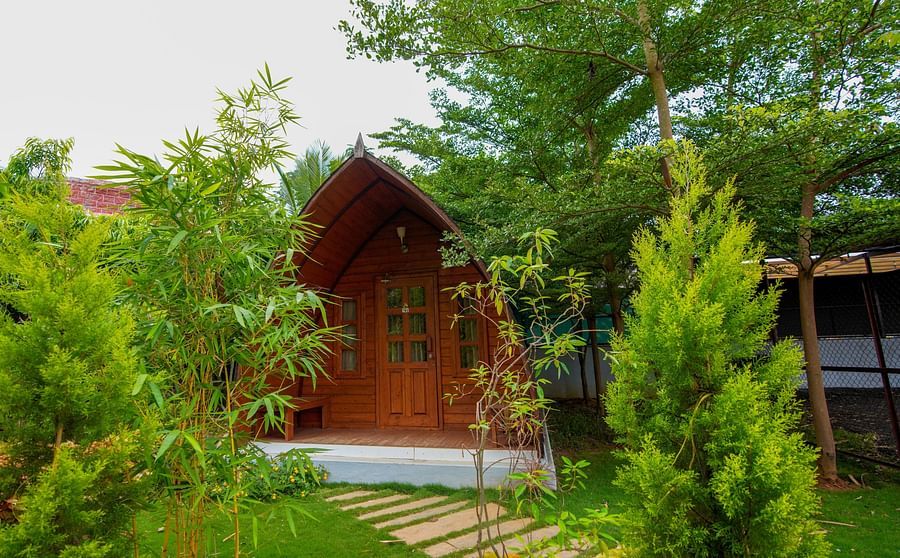A-frame cottage with a stone footpath nestled among lush trees and greenery at GK Hill View Resort