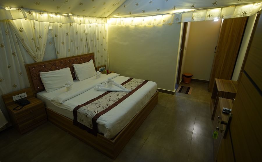 Double bed in the spacious Tent villa of GK Hill View Resort spaciously furnished with bedside tables, cabinets, wardrobe.