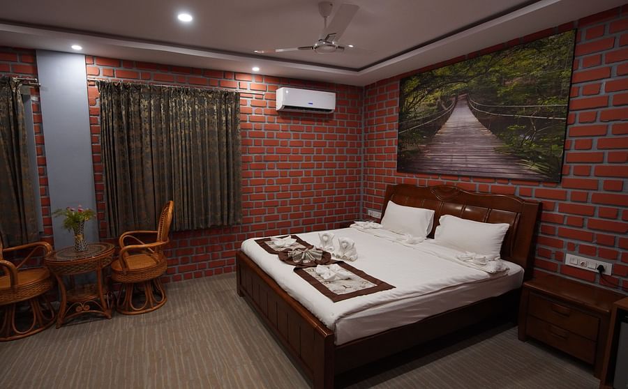 Premier Rooms in GK Hill View Resort furnished with double bed, bedside tables, sitting area for two, wall-mounted AC, curtained windows and romantic lighting.