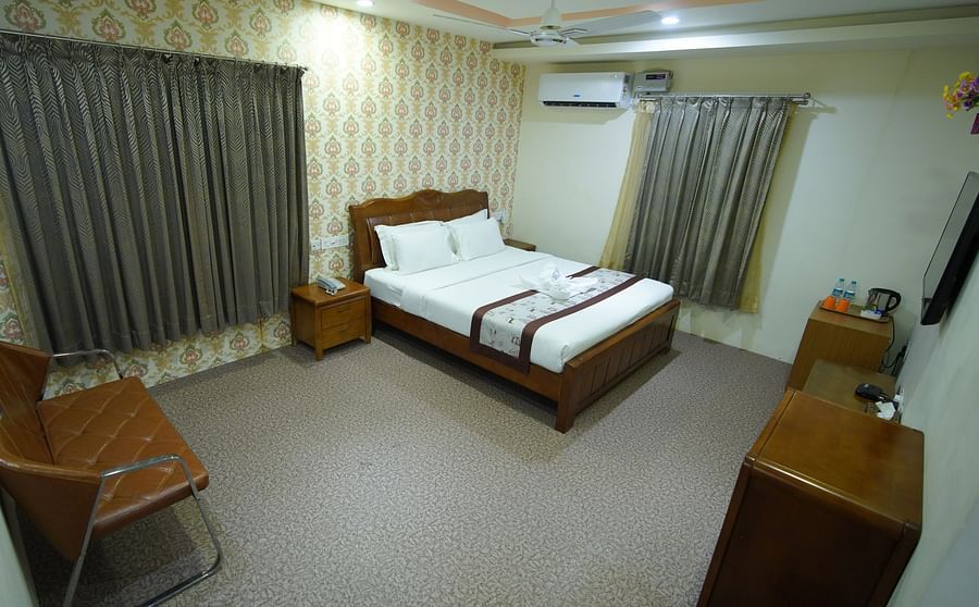 Themed Villas of GK Hill View Resort furnished with a double bed, wall-mounted AC, a chair and curtained windows.