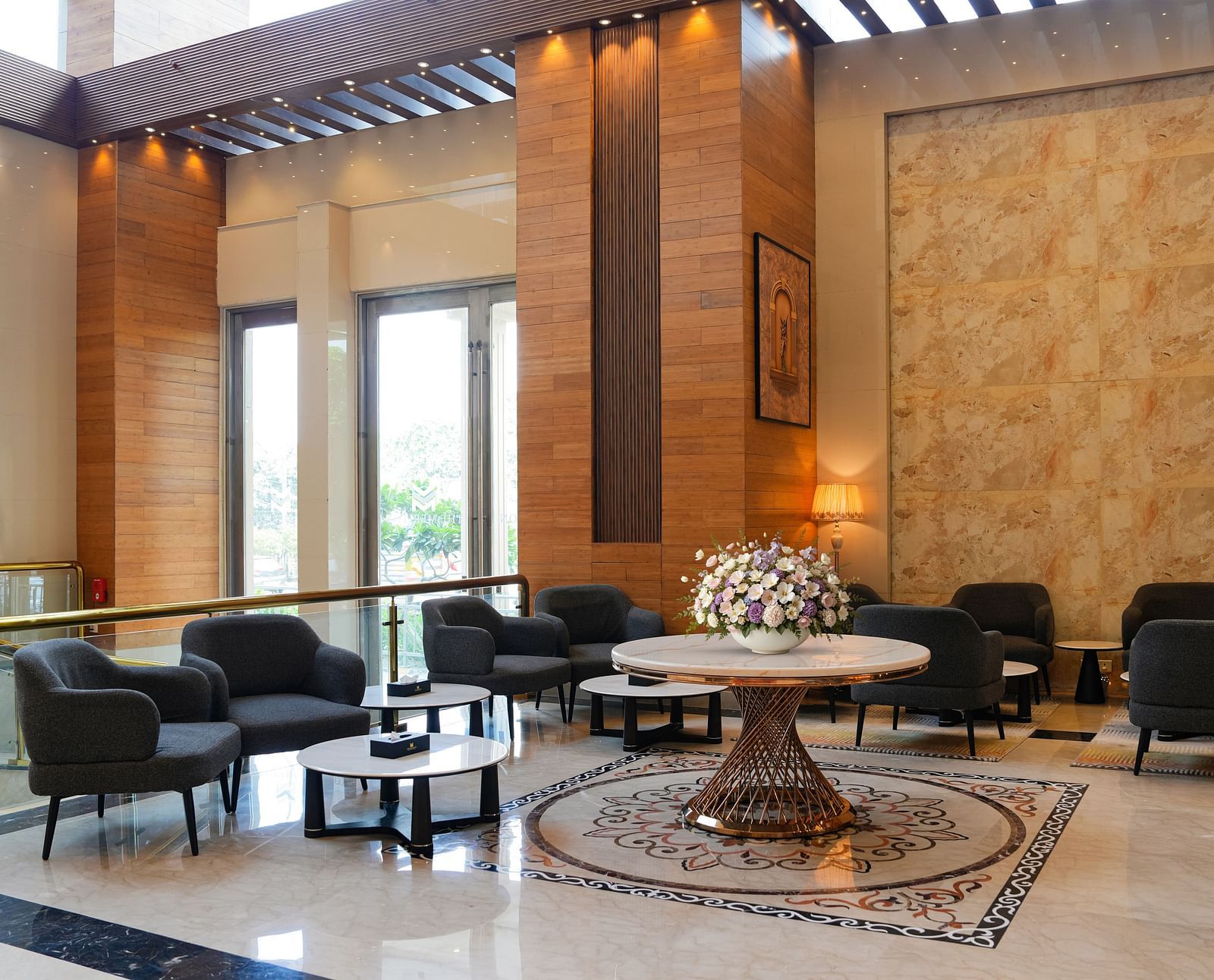 A wide view of The Meriton's sophisticated common area, featuring dark upholstered seating, round tables, and decorative wall panels, suggesting a lounge or bar.