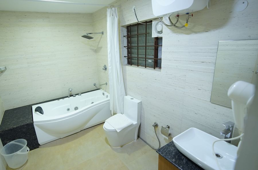 The bathroom of the Themed Villa is furnished with a Jacuzzi, sink and western commode.- GK Hill View Resort
