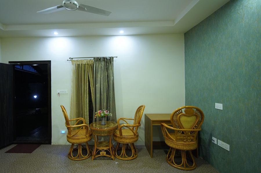 Sitting area placed beside a curtained window and work desk in the spacious Themed Villa of GK Hill View Resort.