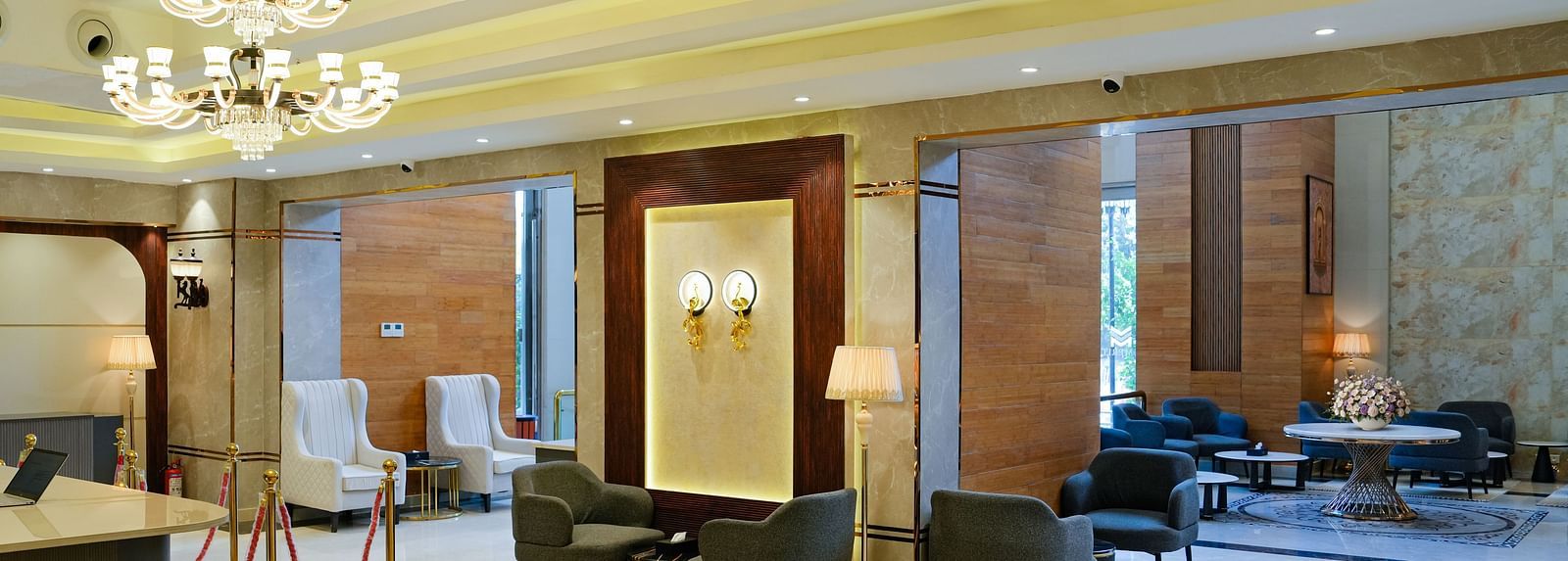 A grand and spacious lobby area at The Meriton, showcasing elegant chandeliers, comfortable seating, and reflective marble flooring.