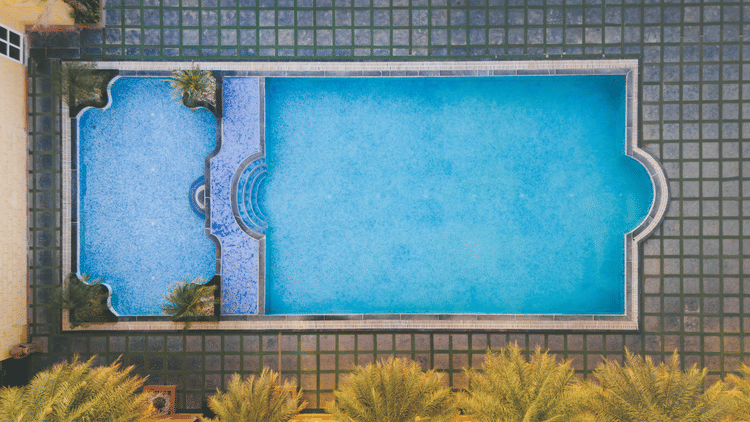 An aerial view image of a swimming and next to it there are several palm trees - The Garden Ananta Elite, Rajkot